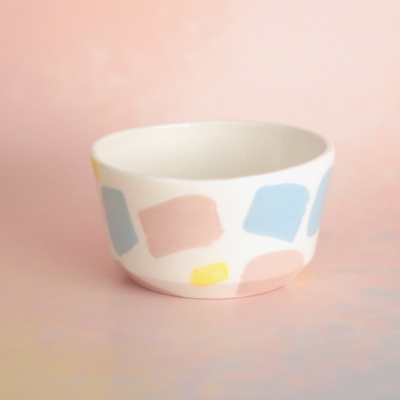 Tigela cerâmica branca com pinceladas pastel em fundo rosa