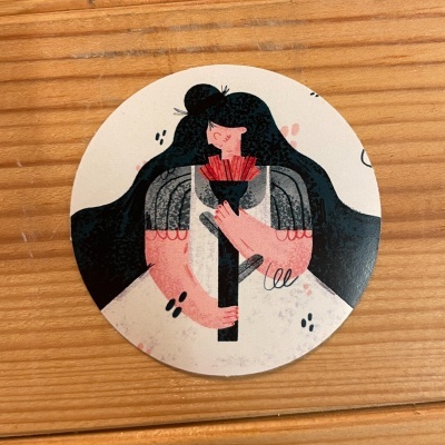 Porta-copos redondo com ilustração de personagem feminina segurando flor.