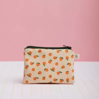 Bolsa pequena bege com padrão de laranjas e fecho preto