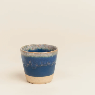 Copo de cerâmica azul com base natural e esmalte azul texturizado.