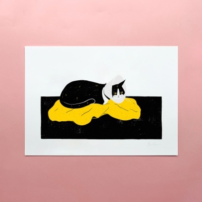 Ilustração de gato preto e branco deitado num tecido amarelo em fundo preto sobre papel branco