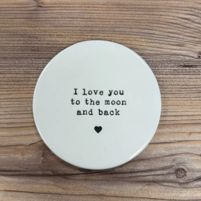 Disco cerâmico branco com texto I love you to the moon and back sobre madeira clara