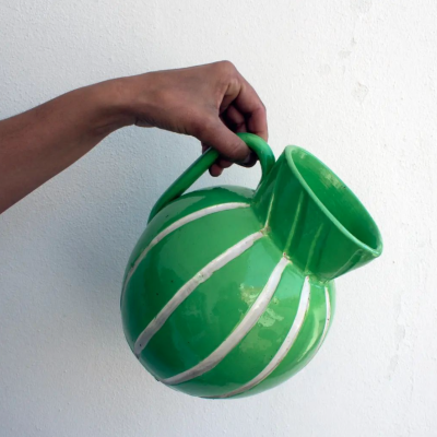 Jarro de cerâmica verde com riscas brancas, segurado por uma mão