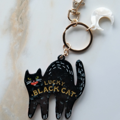 Chaveiro com figura de gato preto e texto LUCKY BLACK CAT, com anel dourado e pendente de lua branca