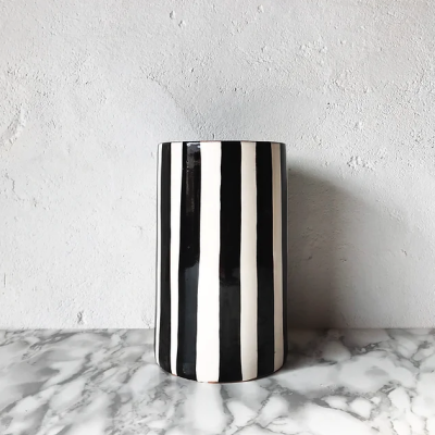 Vaso cilíndrico com riscas verticais preto e branco sobre mesa de mármore