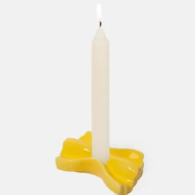 Vela branca acesa em castiçal cerâmico amarelo