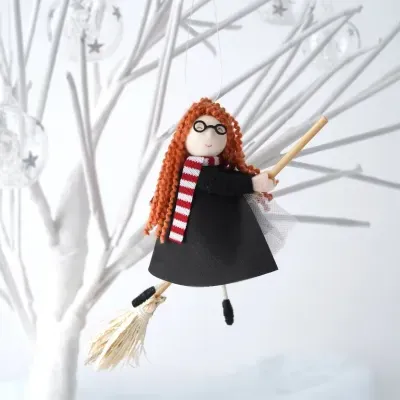 Boneca decorativa com vestido preto e cachecol vermelhor e branco a voar numa vassoura