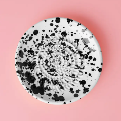 Prato branco com manchas pretas e cinzentas sobre fundo rosa