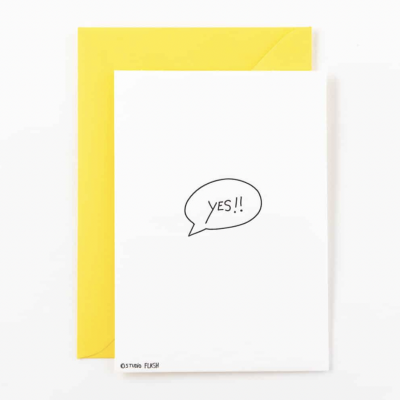 Cartão branco com balão de fala e texto 'YES!!' com envelope amarelo.