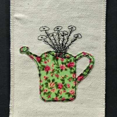 tecido bege com bordado de regador verde floral e flores brancas desenhadas