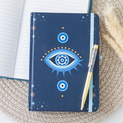 Caderno azul com desenho de olho e caneta dourada sobre superfície rústica.