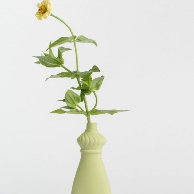 Vaso decorativo verde com flor amarela e folhas verdes