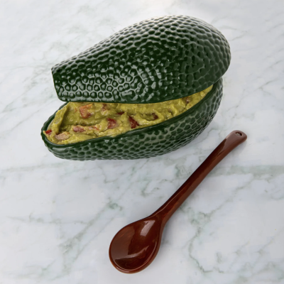 Recipiente em forma de abacate com patê verde e colher castanha sobre mármore branco