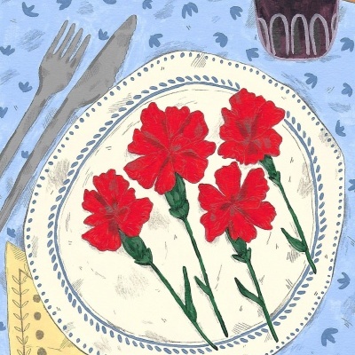 Conjunto de mesa com prato decorado, cravos vermelhos, talheres, guardanapo amarelo e copo roxo sobre toalha azul.