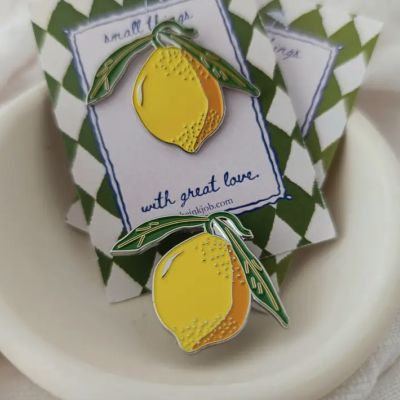 Dois pins limão esmaltados com folhas verdes e cartões brancos com padrão verde
