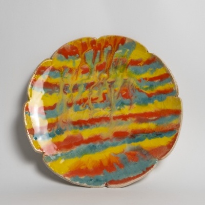 Prato cerâmico decorativo com padrão colorido em faixas laranja, amarelo, azul e verde