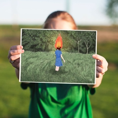 Pessoa segura fotografia de menina em campo verde com cabeça de fogo