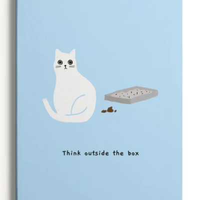 Caderno azul claro com desenho de gato branco e caixa de areia cinzenta, texto 'Think outside the box'