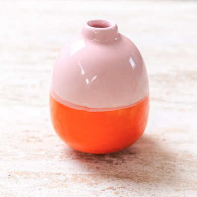 Vaso pequeno de cerâmica rosa claro e laranja sobre superfície clara texturizada