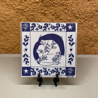 Azulejo decorativo azul e branco com figura humana estilizada e padrão floral