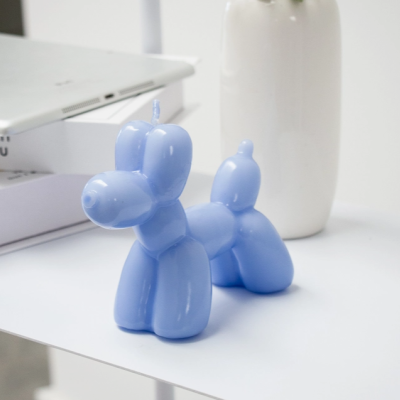 Vela azul em forma de balão de cão sobre mesa branca