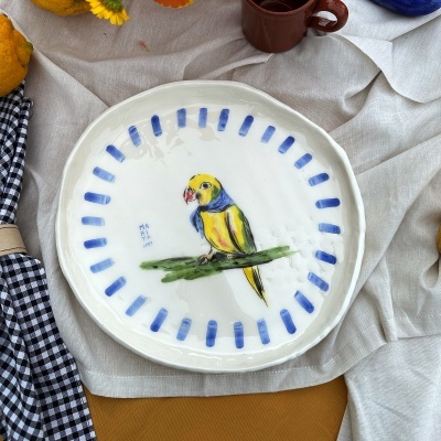 Prato de cerâmica branca com papagaio pintado e borda decorada a azul