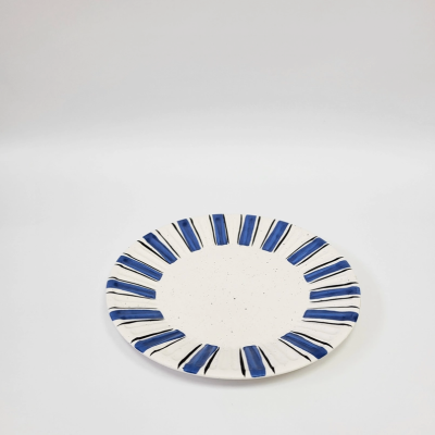 Prato cerâmico redondo branco com padrões azuis e pretos na borda