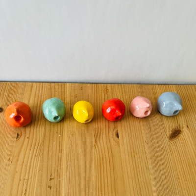 Seis peixes de cerâmica coloridos em linha numa superfície de madeira