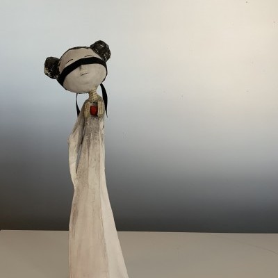 Estátua feminina estilizada com vestido branco e cabelo preso em dois coques