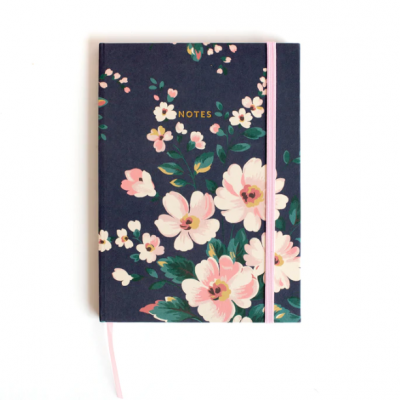 Caderno de capa dura azul com flores rosas e verdes, elástico cor-de-rosa e texto 'NOTES' dourado