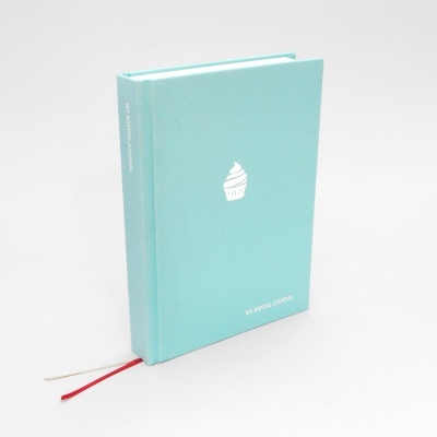 Caderno azul claro com símbolo de cupcake branco e texto 'MY BAKING JOURNAL'