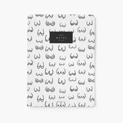 Caderno branco com desenhos a preto de vários tipos de seios e etiqueta preta com texto branco