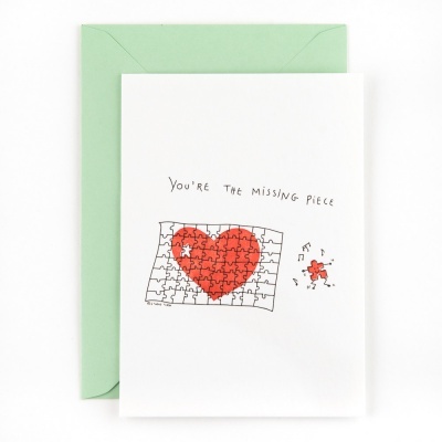 Cartão branco com coração vermelho em puzzle e envelope verde