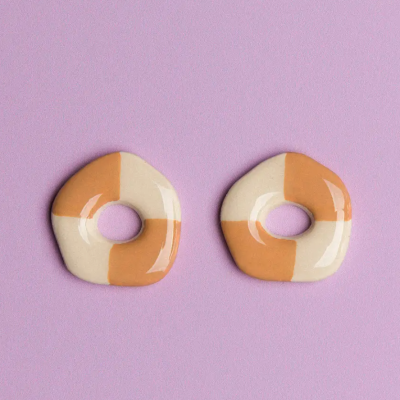 Par de brincos cerâmica creme e laranja em fundo roxo