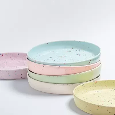 Conjunto de pratos cerâmicos coloridos com padrão salpicado.