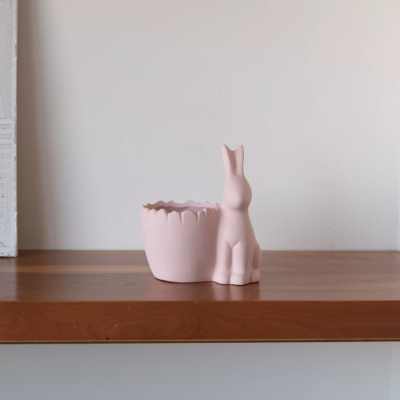 Vaso rosa claro com figura de coelho decorativa em prateleira de madeira