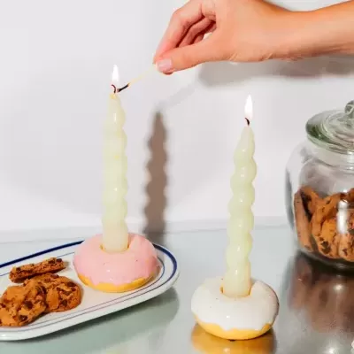 Castiçais em forma de velas onduladas com base de donuts glacados e biscoitos de chocolate próximos