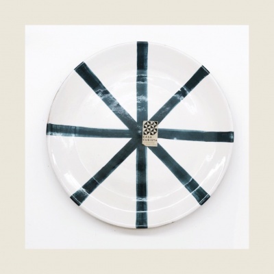 Prato cerâmico branco com riscas pretas e etiqueta 'CASA CERÂMICA'.