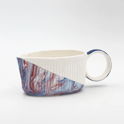Caneca de cerâmica com padrão azul, vermelho e branco e cabo circular azul