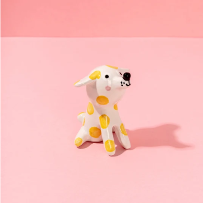 Figura decorativa de cão branco com manchas amarelas em fundo cor-de-rosa