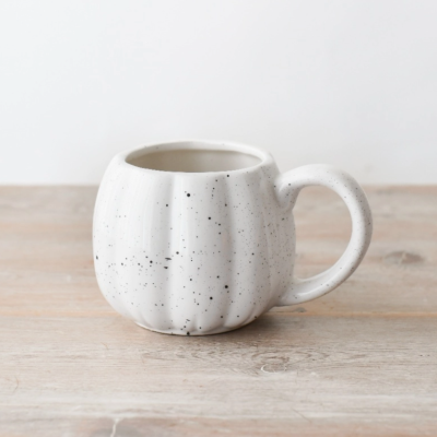 Caneca de cerâmica branca com manchas pretas e forma arredondada