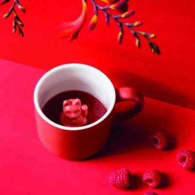 Caneca vermelha com figura de gato rosa e framboesas em fundo vermelho