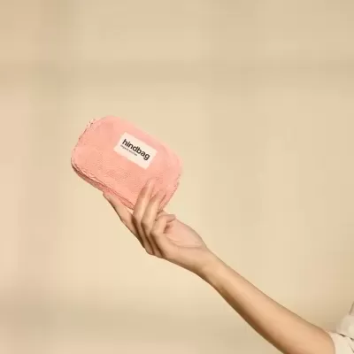 Mala pequena rosa felpuda com etiqueta hindbag segurada por mão feminina