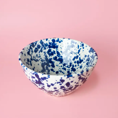 Tigela de cerâmica branca com manchas azuis assentada em superfície rosa
