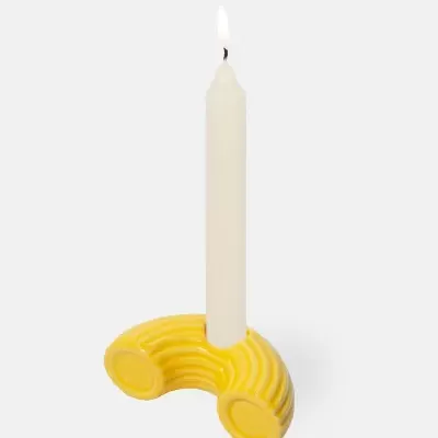 Castiçal amarelo de cerâmica com vela branca acesa