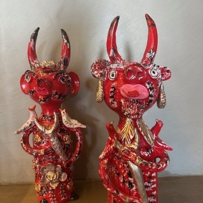 Duas esculturas vermelhas com chifres e detalhes dourados e pretos em cerâmica