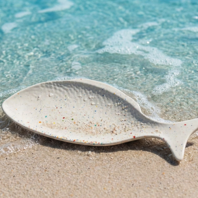 Prato decorativo em forma de peixe na areia junto ao mar