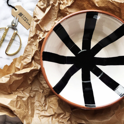 Tigela cerâmica riscas pretas sobre fundo branco com borda castanha, papel castanho amarrotado, tesoura dourada, etiqueta CASA CUBISTA