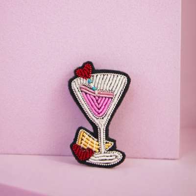 Cracha bordado de copo de cocktail com bebida rosa e decorações vermelhas e amarelas