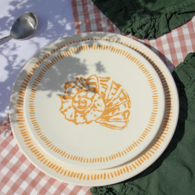 Dois pratos de cerâmica branca com padrão laranja sobre toalha xadrez rosa e branca